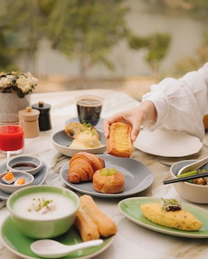 Una mesa con diferentes alimentos, incluyendo pasteles, un tazón de sopa y una taza de café.