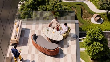 Une terrasse sur le toit avec un sol à carreaux, des sièges extérieurs et un jardin aménagé.