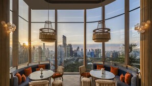 A modern interior with a city view, round tables, and comfortable seating. - Andaz One Bangkok, by Hyatt (Bangkok)