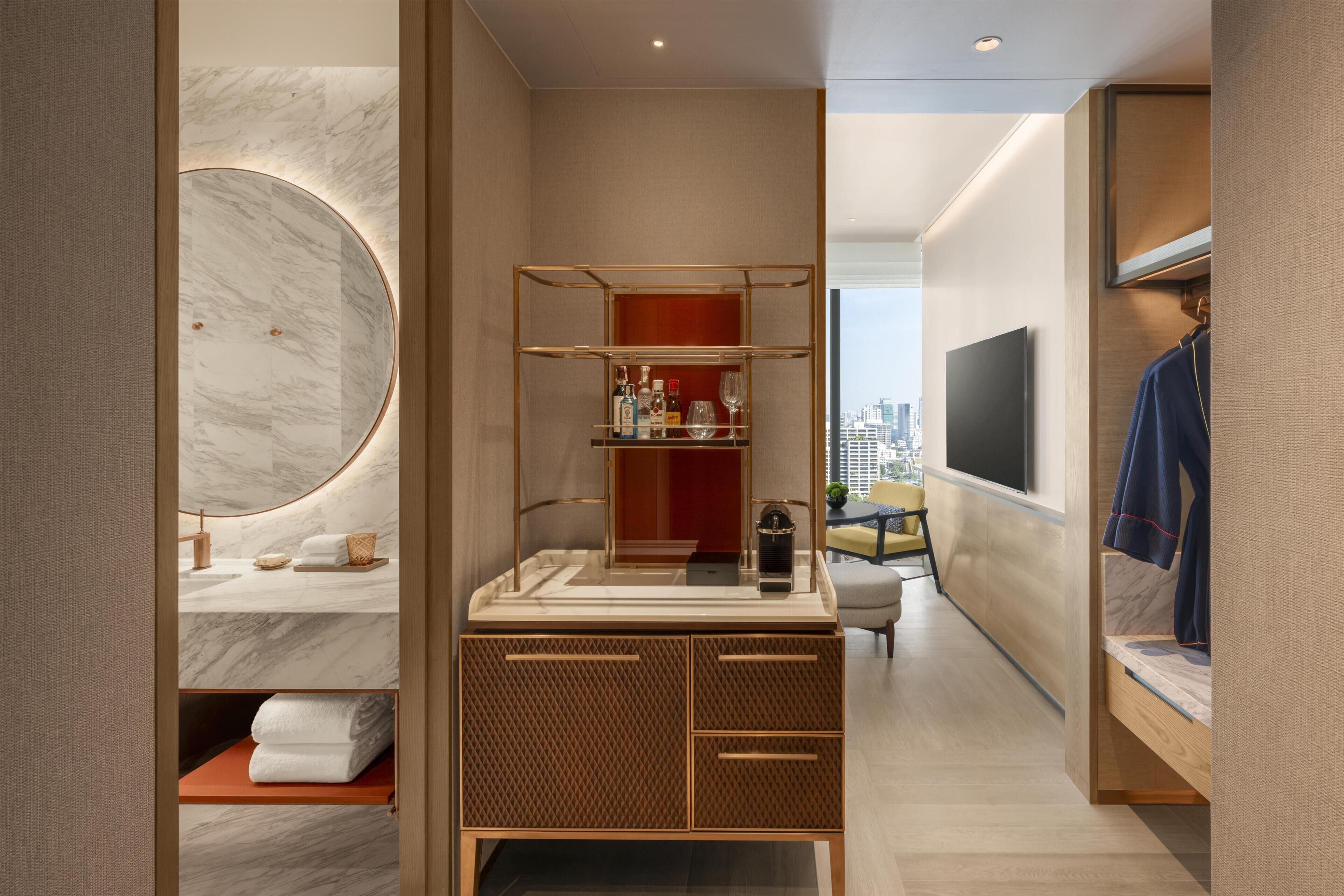 Una habitación de hotel moderna con un tocador de mármol, televisión integrada, armario y vistas a la ciudad.
