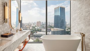 A modern bathroom with a freestanding bathtub, marble countertops, and a large mirror.