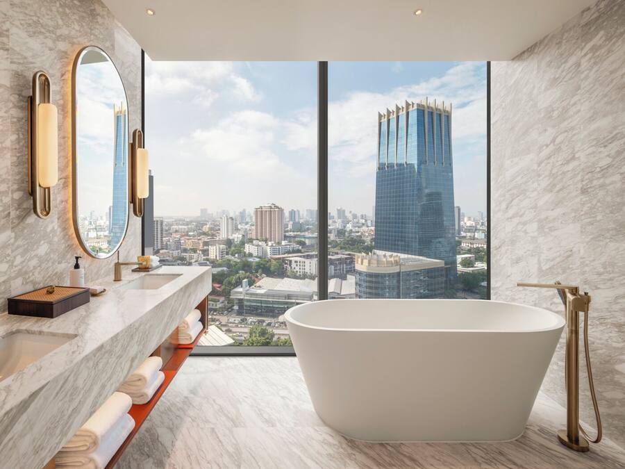 A modern bathroom with a freestanding bathtub, marble countertops, and a large mirror.