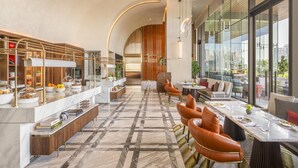A modern hotel lobby with a marble floor, a long dining table, leather chairs, and a view of the city through large windows. - Andaz One Bangkok, by Hyatt (Bangkok)
