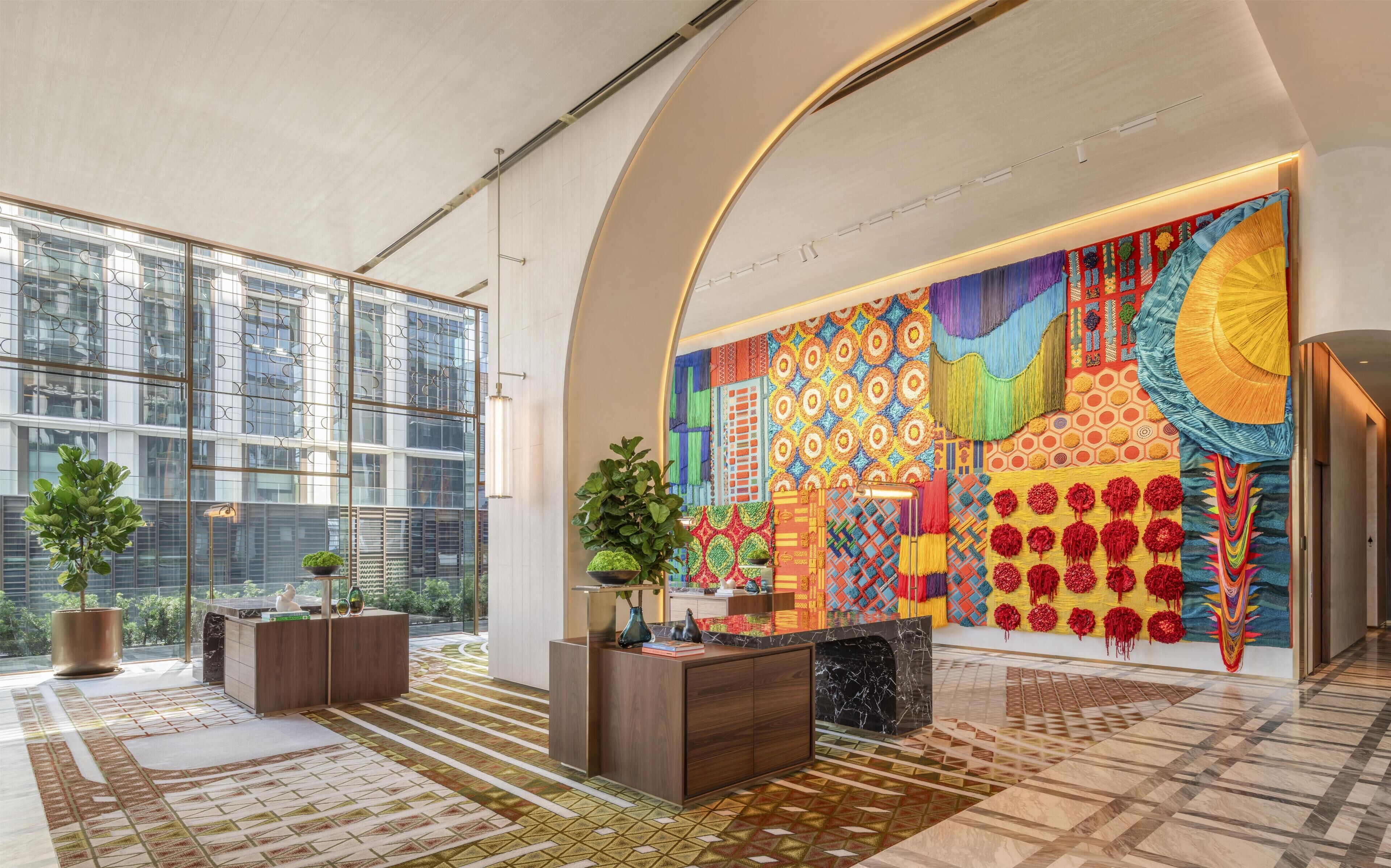 Un hall d’entrée spacieux, doté de grandes fenêtres, d’un comptoir d’accueil central et d’une fresque murale aux couleurs vives.
