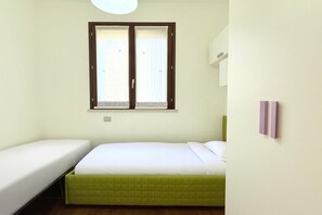 Una habitación con una cama, una ventana y una lámpara fijada a la pared.