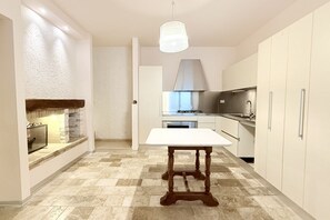 Eine moderne Küche mit einem weißen Tisch, einem eingebauten Backofen und einer Pendelleuchte.