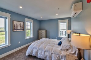 Une chambre à coucher avec un lit, une commode et deux fenêtres.