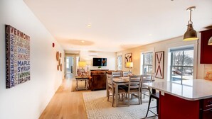 A spacious living area with a dining table, sofa, and a kitchen with a red accent wall.