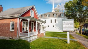 A historic building with a prominent steeple, a signboard for the Stowe Public House, and a well-maintained lawn.
