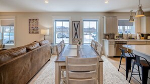 A modern kitchen with a dining area, a sofa, and a view of the outside. - Cady Suite at 109 Main (Stowe)