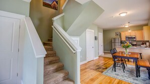 A staircase leading to a second floor, a dining area with a table and chairs, and a kitchen area with appliances. - Sterling Suite at 109 Main (Stowe)