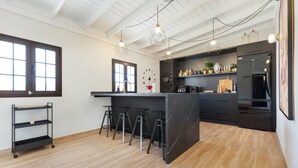 A modern kitchen with a central island, bar stools, pendant lighting, and a wooden floor. - Vacation Home 'Esencia House Bajo Las Estrellas' with Mountain View, Private Pool and Wi-Fi (Puerto del Rosario)