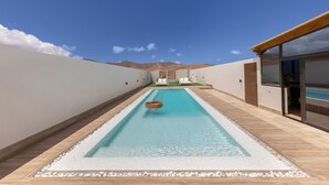 A rectangular pool with a wooden deck, white walls, and a mountain view. - Vacation Home 'Esencia House Bajo Las Estrellas' with Mountain View, Private Pool and Wi-Fi (Puerto del Rosario)