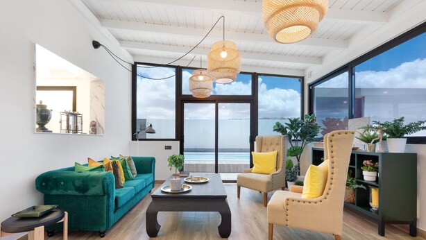 A modern living room with a sofa, armchair, coffee table, and large windows offering a view of the sea. - Vacation Home 'Esencia House Bajo Las Estrellas' with Mountain View, Private Pool and Wi-Fi (Puerto del Rosario)