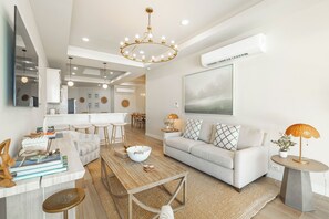 Een moderne woonkamer met een bank, salontafel en een eethoek met stoelen.