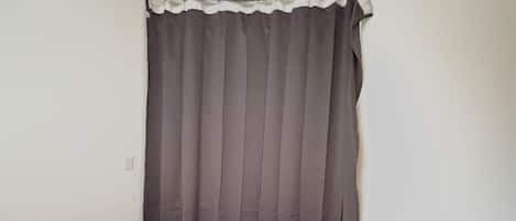 A bedroom with a bed, a curtain, and a radiator.