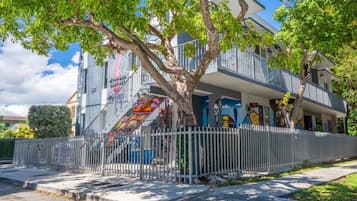 Un bâtiment à deux étages avec un balcon, un arbre devant et une clôture.