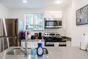 A modern kitchen with stainless steel appliances, a window with a view, and a zebra artwork on the wall. - Prime Location | Free Parking |By Nightlife & Eats (Miami)