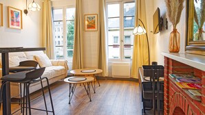 A cozy room with a sofa, two round tables, and a brick fireplace.