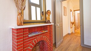 A hallway with a brick fireplace, a mirror, and a door leading to another room.