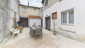 A courtyard with a dining table and chairs, a potted plant, and a small outdoor seating area. - Le fil de l'Evre - Au coeur des Mauges (Le May-sur-Èvre)