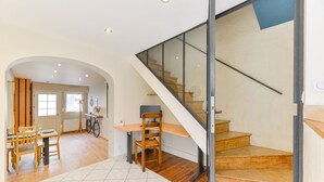 A spacious living area with a wooden staircase, a dining table with chairs, and a bicycle. - Le fil de l'Evre - Au coeur des Mauges (Le May-sur-Èvre)