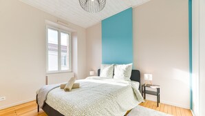 A bedroom with a bed, a nightstand, a window, and a blue accent wall. - Le fil de l'Evre - Au coeur des Mauges (Le May-sur-Èvre)