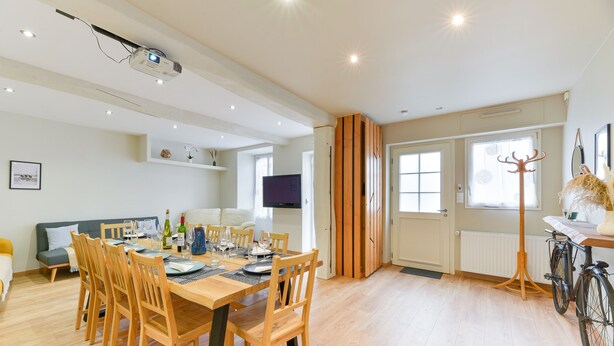 A modern living room with a dining area, wooden furniture, a television, and a bicycle. - Le fil de l'Evre - Au coeur des Mauges (Le May-sur-Èvre)
