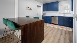 Eine moderne Küche mit blauen Schränken, einer Holzinsel und einem grünen Stuhl.