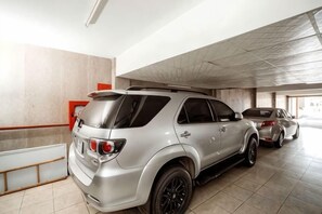Een parkeergarage met een zilveren SUV en een witte auto.