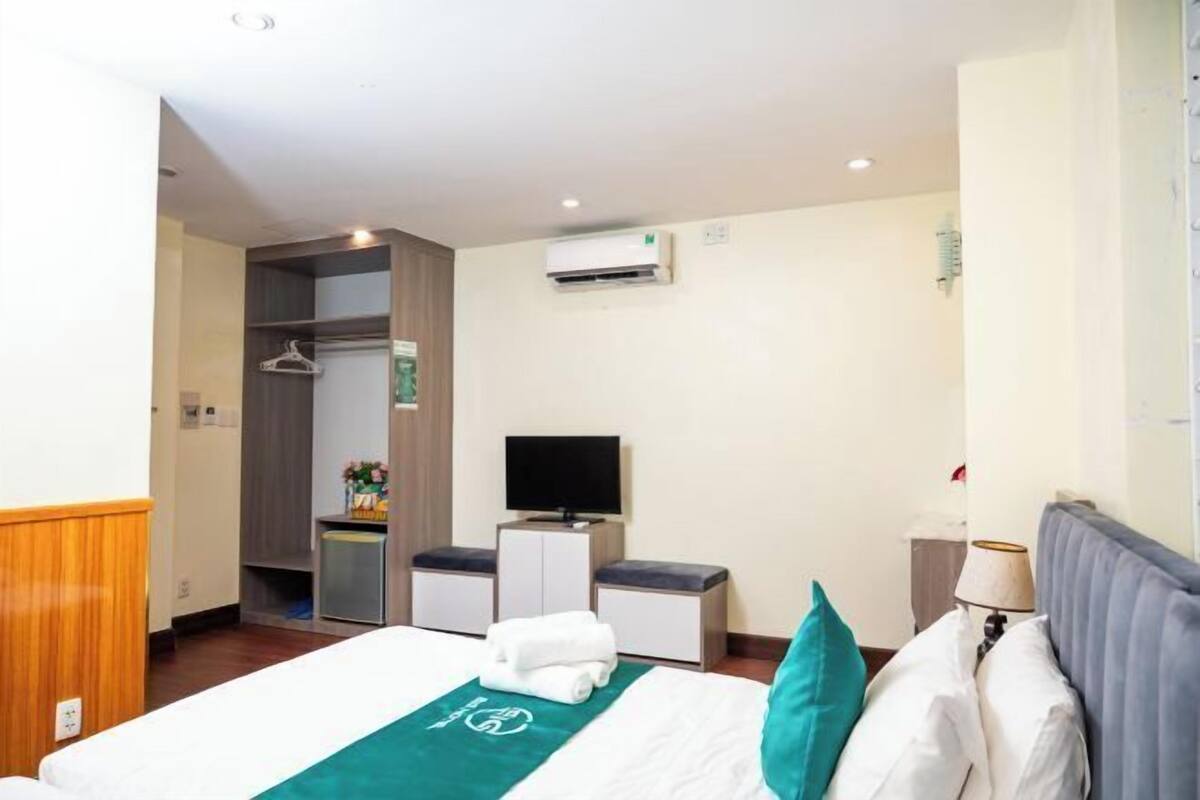 Een hotelkamer met een bed, een televisie, een bureau en een kledingkast.