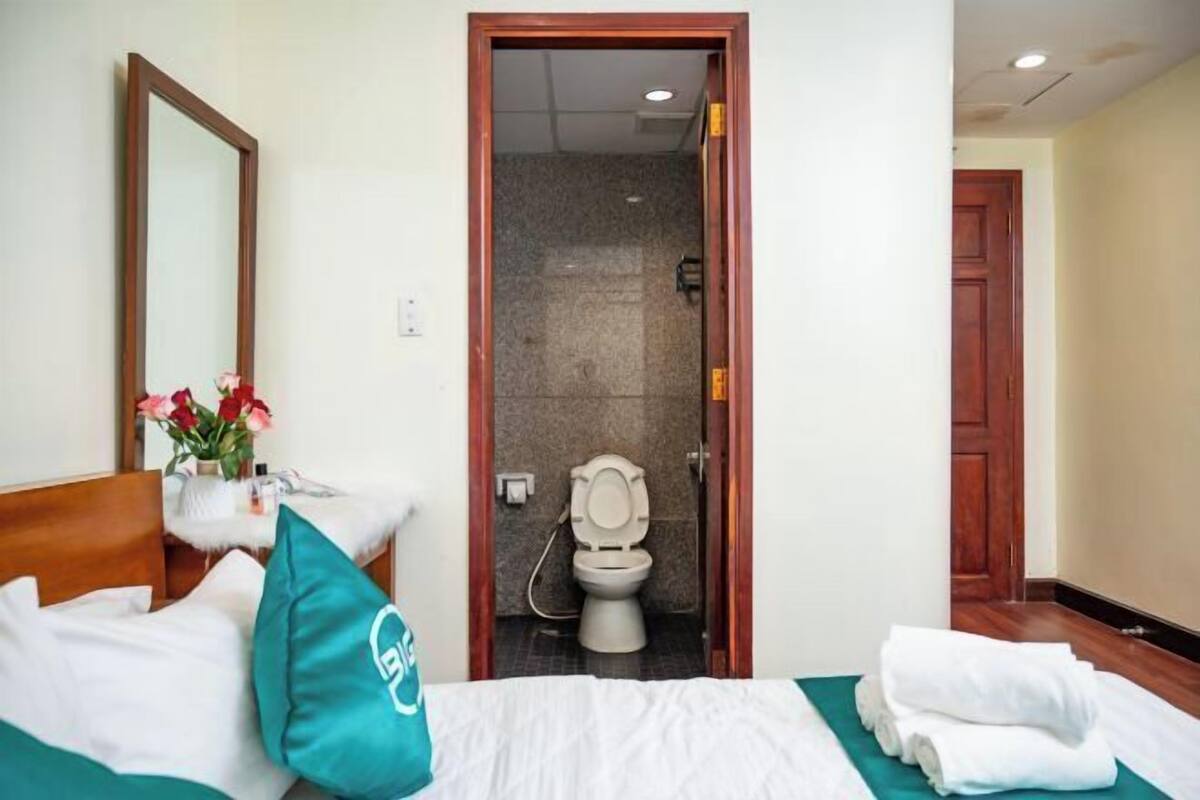 Een hotelkamer met een bed, een badkamer met toilet en douche, en een houten deur.