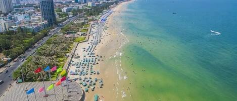 A coastal beach with a promenade, umbrellas, and a clear view of the sea.