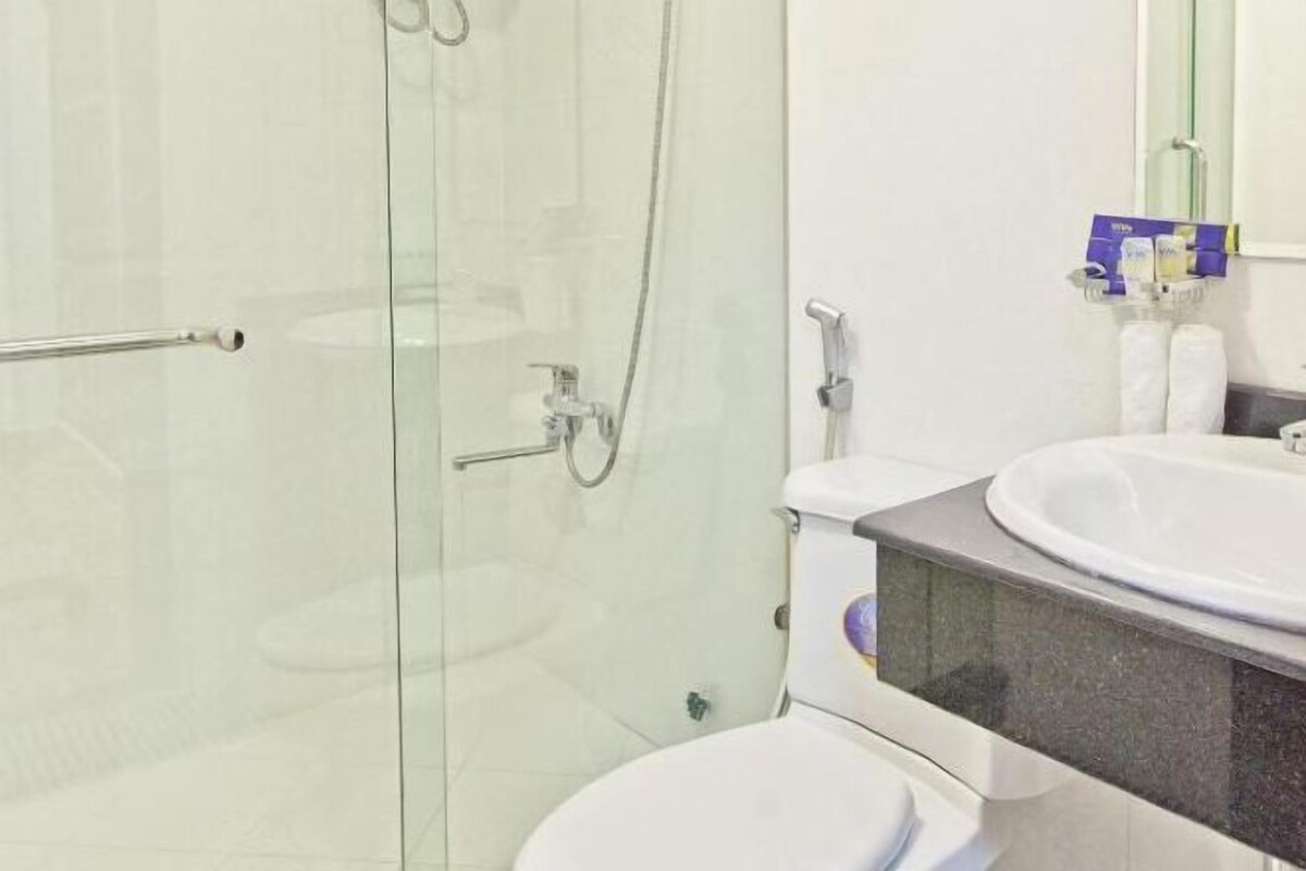 Une salle de bain moderne avec une douche à parois de verre, des toilettes blanches et un lavabo doté d’un plan de travail en marbre.