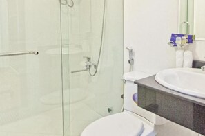 Une salle de bain moderne avec une douche à parois de verre, des toilettes blanches et un lavabo doté d’un plan de travail en marbre.