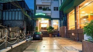 Ein Hotel-Empfangsbereich mit einem davor geparkten Auto, einer Absperrkette und einer Treppe zum Eingang.