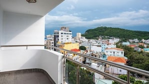 Ein Balkon mit Blick auf eine Küstenstadt, einschließlich Gebäude und einer Hügelkette.