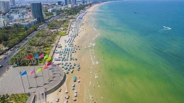 Eine Küstenstadt mit Strand, Promenadenweg und städtischen Gebäuden.