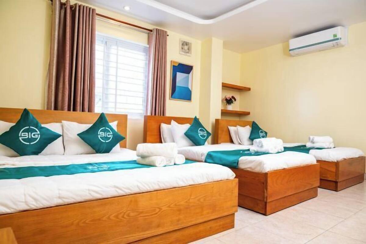 Een hotelkamer met drie houten bedden, elk met passende kussens en een blauwgroene sprei.