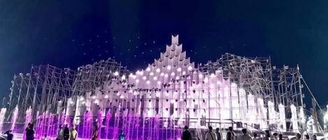 Una estructura grande e iluminada con un diseño escalonado, rodeada por una multitud de personas.