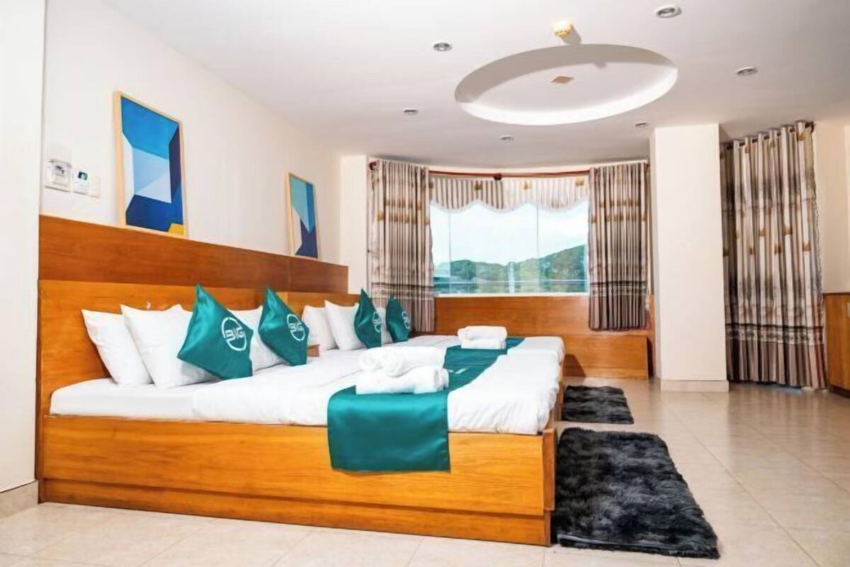 Een hotelkamer met een groot bed, uitzicht op de omgeving, een houten hoofdeinde en een modern plafond.