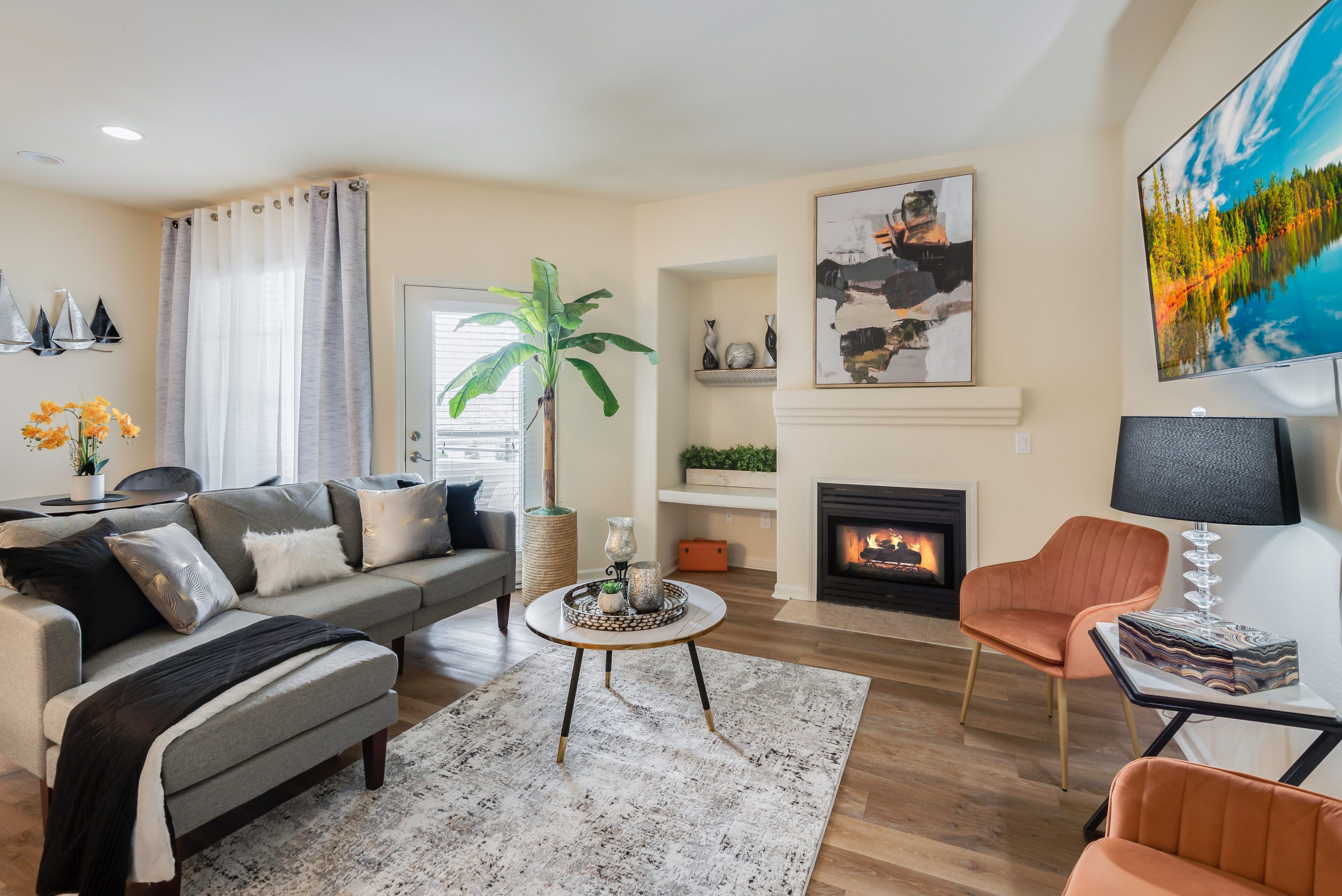 Un salon moderne comprenant un canapé, des fauteuils, une table basse, une cheminée et un téléviseur.