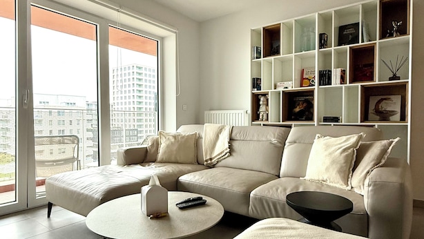 Ein modernes Wohnzimmer mit einer großen Couch, einem Couchtisch und einem Bücherregal.