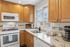 A kitchen with wooden cabinets, a white stove, a microwave, and a coffee maker.