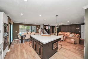 Une cuisine moderne dotée d’un îlot central, de planchers en bois et d’un coin repas avec un escalier menant à une mezzanine.