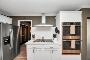 Une cuisine moderne dotée d’appareils électroménagers en acier inoxydable, de meubles blancs et d’un îlot central avec un évier.