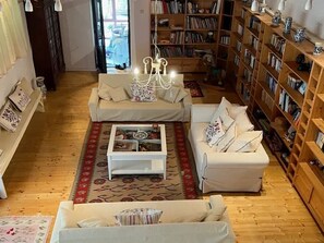 Ein gemütliches Wohnzimmer mit zwei weißen Sofas, einem Couchtisch und einem Bücherregal voller Bücher.