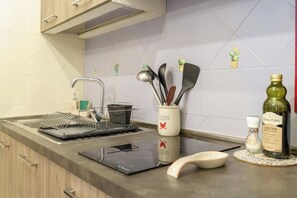 Eine Küche im modernen Design, mit Spüle, Geschirrgestell, Schneidebrett und Besteckhalter mit verschiedenen Küchenutensilien.