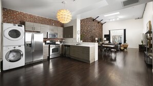 Una cocina moderna con pared de ladrillo decorativa, electrodomésticos de acero inoxidable y zona de comedor con vistas.