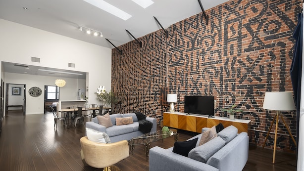 Una sala de estar moderna con una pared de ladrillo, un sofá, una mesa de centro y un televisor.